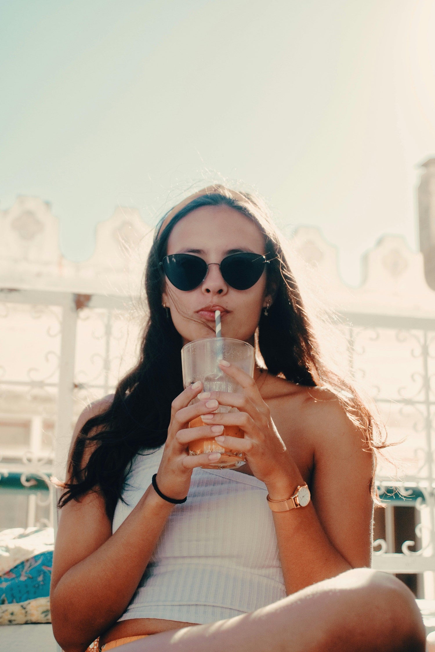 A woman sitting down wearing oversized sunglasses