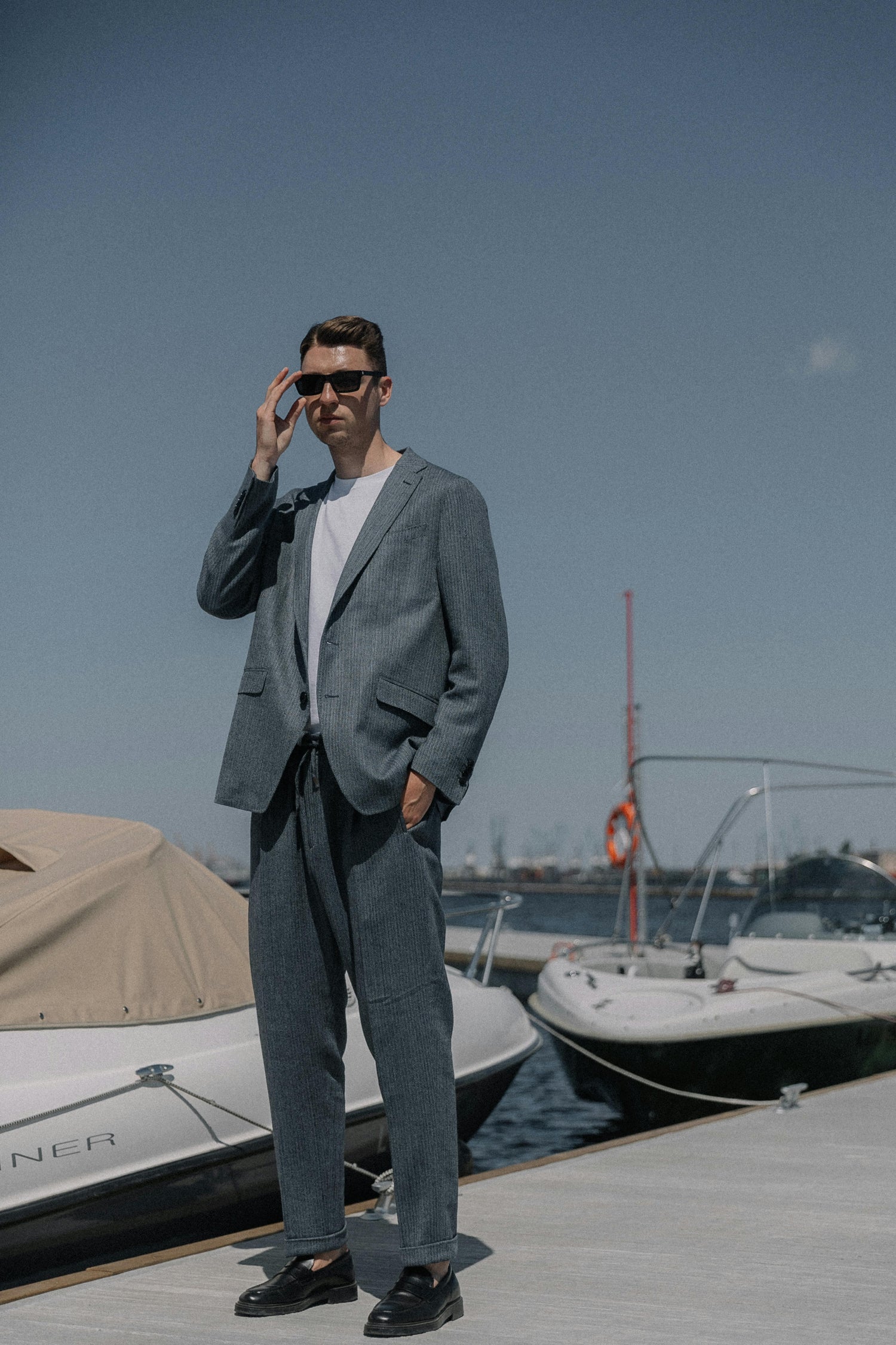 Man standing at dock wearing a suit with sunglasses